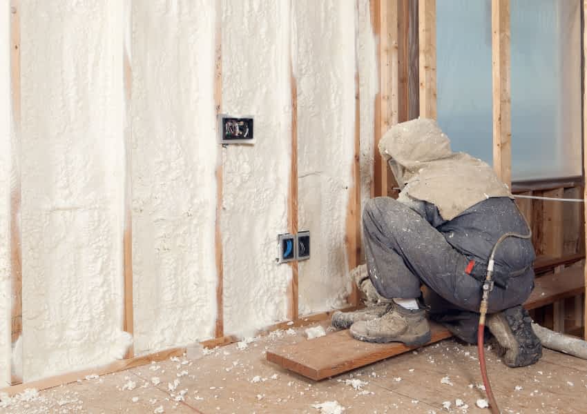 Image of a Man Applying Spray Foam Insulation to a Basement Wall