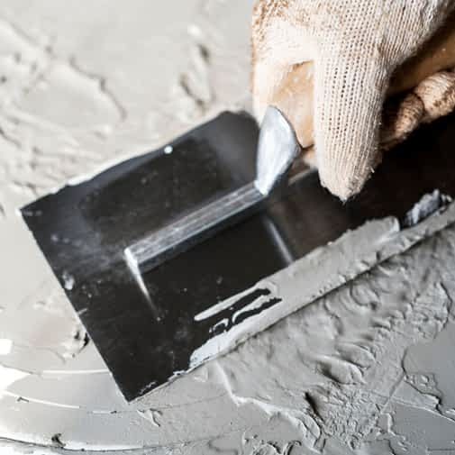Basement Waterproofing Contractor New York - A Contractor Applying Cement to Basement Floor