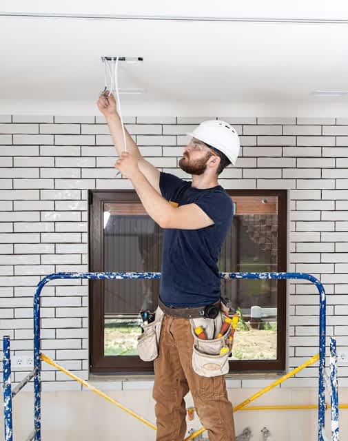 Basement Finishing and Remodeling Contractor New York - A Man Painting a Ceiling on a Scaffold