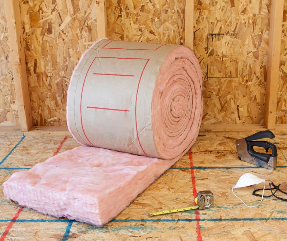 Fiberglass Insulation Contractor New York - A Roll of Pink Fiberglass Insulation Next to Some Gloves and Tools