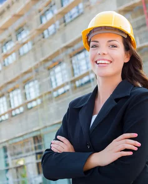 Zavza Seal: About Us - A Construction Superintendant Smiling at the Camera Wearing a Black Suit and Yellow Hardhat